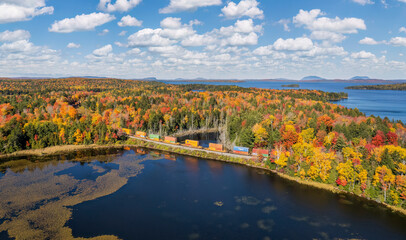Freight train in autumn panorama at Moosehead Lake - Maine - Train tracks along the lakeshore