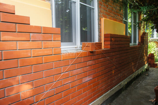 Reconstruction of country house. Insulation of brick facade of facade with help of penoplex. Facade decoration of walls with facing bricks close to thermal insulation layer.