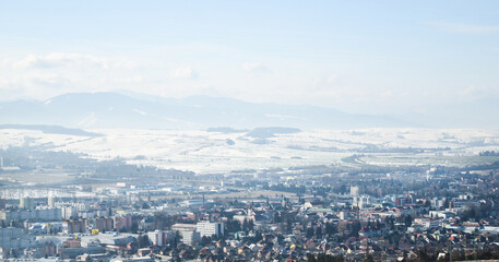 Obraz premium View from hill Nicovo to the part of Liptovsky Mikulas city in the winter and to Low tatras. Slovakia, Liptov region. Snowy, cold and sunny weather.