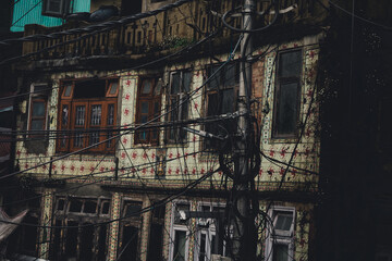 Fototapeta na wymiar Old abandoned building with beautiful tiles on the wall - Electric pole with a lot of wires in the foreground