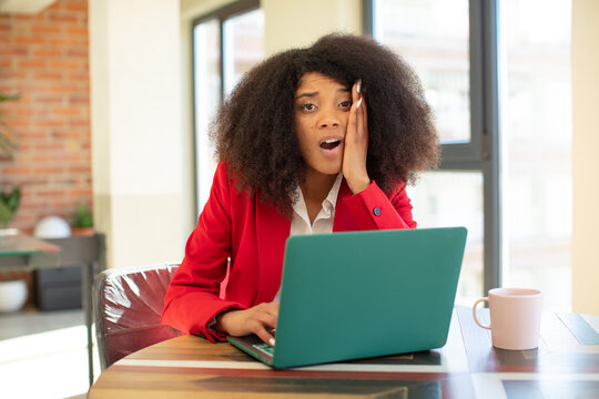 pretty afro black woman feeling extremely shocked and surprised. businesswoman and laptop concept