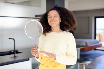 pretty afro black woman smiling cheerfully, feeling happy and showing a concept. home chef concept