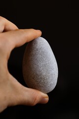fingers grabing a grey rock in black background