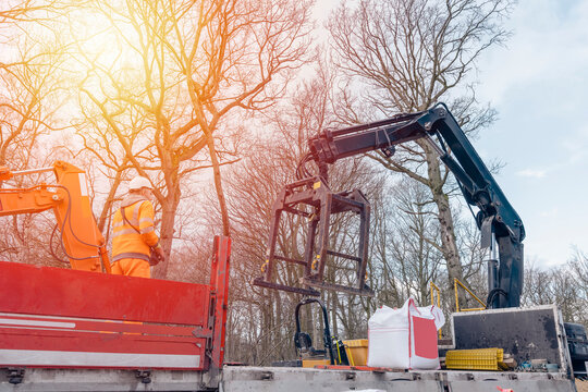 Dropside flatbed HIAB crane lorry with brick grab attachment deliver materials on construction site and offloading them