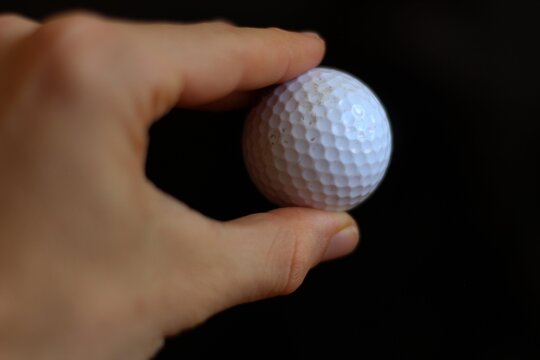fingers grabing a golf ball in black background