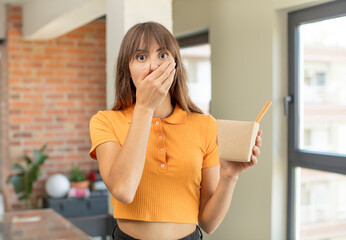 young pretty woman covering mouth with a hand and shocked or surprised expression. ramen bowl noodles concept