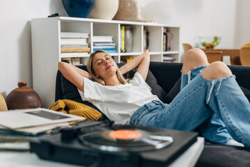 Caucasian woman relaxing with music from gramophone at home