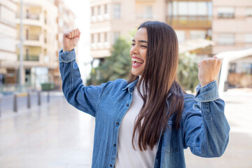 Fototapeta premium pretty young adult woman feeling happy, positive and successful, celebrating victory, achievements or good luck