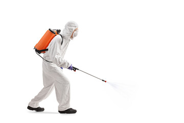 Full length profile shot of a man in a hazmat suit applying pesticide