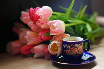 Fototapeta na wymiar Cup of coffee and pink tulips