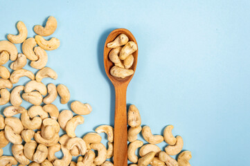 Cashew nuts in a wooden spoon on a blue background