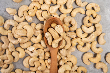 Cashew nuts in a wooden spoon on a gray marble stone background