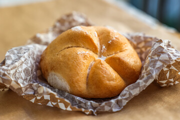 Serviette with Kaiser roll on parchment paper, closeup