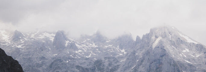 Panorama of the rocky mountains with little snow on a cloudy day