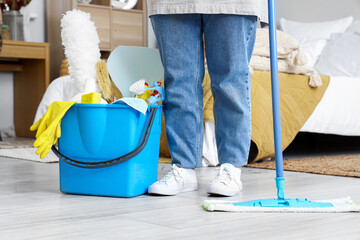 Housewife with cleaning supplies in bedroom