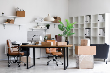 Interior of office with workplaces and cardboard boxes on moving day