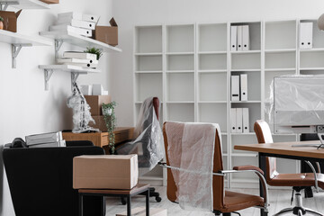 Interior of office with workplaces and cardboard boxes on moving day
