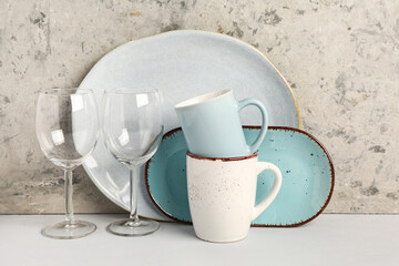 Set of different dishes on table near grey grunge wall
