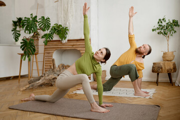 Young attractive family couple practicing yoga stretching workout at home