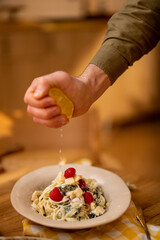 Squeezing lemon into pasta meal, close-up