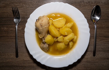 Potato soup with chicken drumsticks on wooden kitchen counter