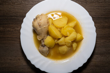 Potato soup with chicken drumsticks in plate and wooden background