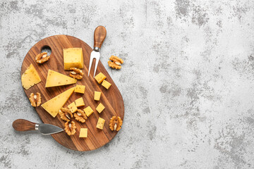 Wooden board with pieces of tasty cheese on grunge background
