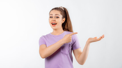 Lovely smiling young woman with long hair pointing finger right, showing advertisement, promo offer, standing in casual t shirt over white background