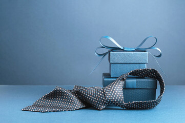 Happy Fathers Day background banner. Two blue gift boxes with ribbon bow and necktie on dark blue...