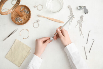 Female hands with beautiful ring, cleaning tools and jewelry on light background