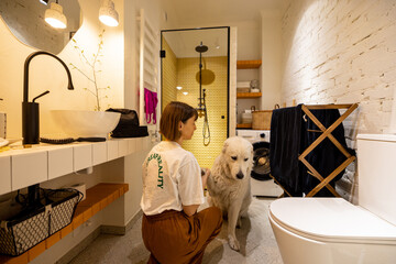 Woman cares her dog during washing routine in bathroom. Domestic lifestyle and love with pets concept
