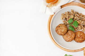 Cutlets with buckwheat, mushrooms and parsley on white table in kitchen