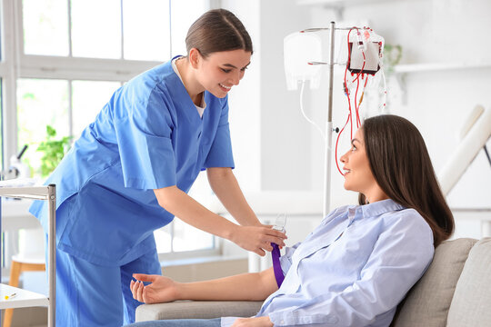 Female nurse preparing young donor for blood transfusion in clinic
