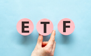 Hand holding pink cards with the word ETF-Exchange Traded Funds.