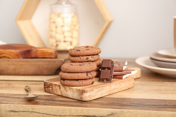 Board with cookies and chocolate on wooden table in kitchen