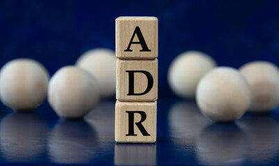 ADR - acronym on wooden cubes on a blue background with wooden balls