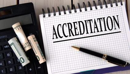 ACCREDITATION - word in a notebook on the background of a calculator and banknotes