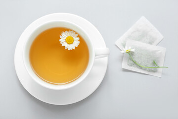 Cup of aromatic chamomile tea on white background
