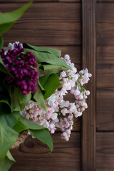 a bouquet of lilacs in a vase on a wooden background. Floral design of the bouquet