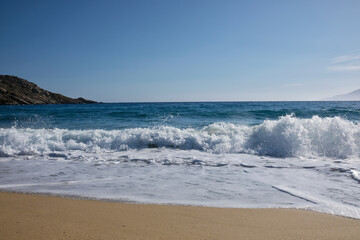 Waves and sea foam at the windy beach of Mylopotas in Ios Greece