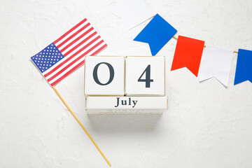Fototapeta na wymiar Cube calendar with 04 JULY date, USA flag and colorful garland on white grunge background. Independence Day celebration