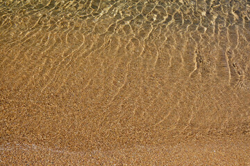 Close up of the beautiful sandy beach and the crystal clear waters of Kalamos in Ios Greece