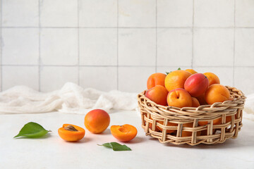 Wicker bowl with fresh apricots on white table