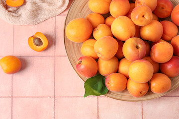 Plate with fresh apricots on pink tile table