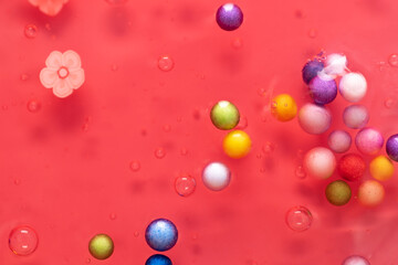 Colorful gel texture, clear skincare cream with bubbles and decorative figurines background, transparent beauty serum, colored cosmetic product close up