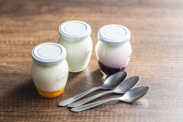White and fruit yogurt in jar on wooden table.