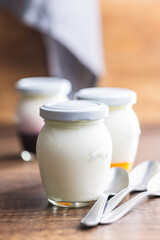 White yogurt in jar on wooden table.