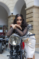 Sexy young woman is posing on a vintage motorcycle  looking at the camera. Vertically. . 