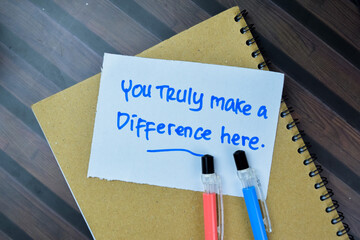 Concept of You Trully Make a Difference Here write on sticky notes isolated on Wooden Table.