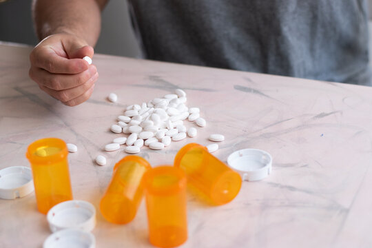 Hand taking a medicine pill of a mount of drugs on table